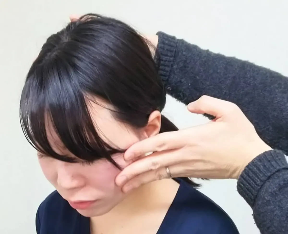小顔矯正の施術中、手で顔のラインを整えている様子